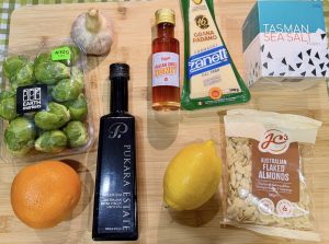 ngredients for air fryer Brussels sprouts including fresh Brussels sprouts, orange, lemon, garlic, hot honey, olive oil, almonds and Grana Padano